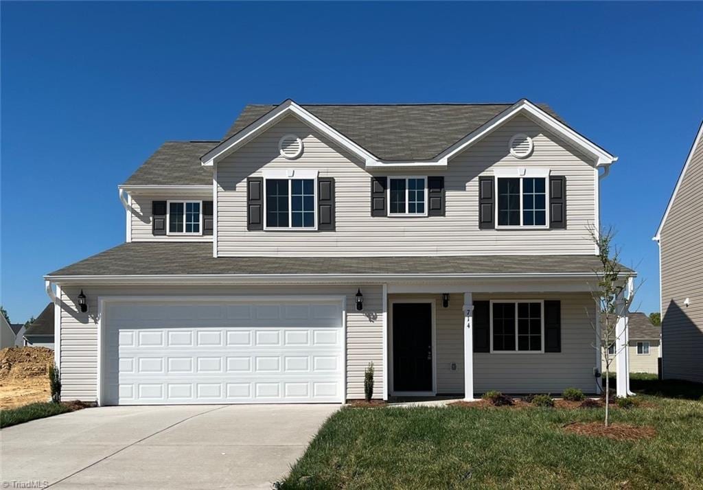 traditional-style house with concrete driveway, a front yard, and an attached garage