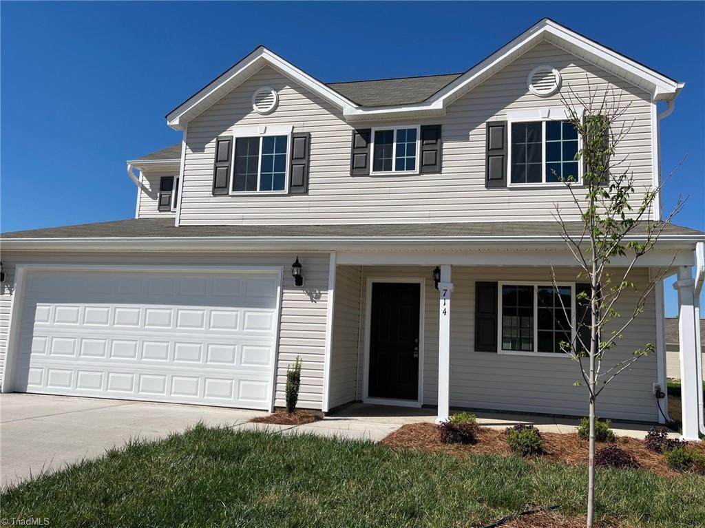 traditional-style home featuring an attached garage, covered porch, and concrete driveway