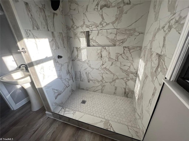 bathroom with a tile shower and wood-type flooring