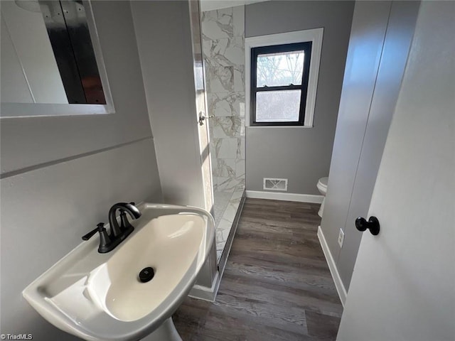 bathroom featuring a tile shower, toilet, and hardwood / wood-style flooring