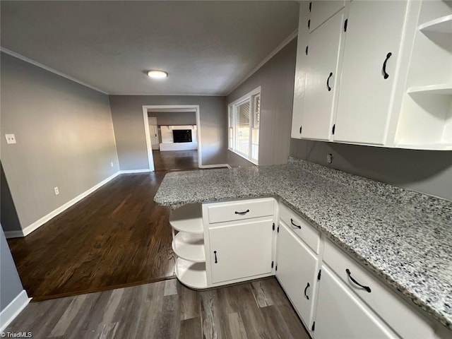 kitchen with light stone countertops, kitchen peninsula, dark hardwood / wood-style floors, and white cabinets