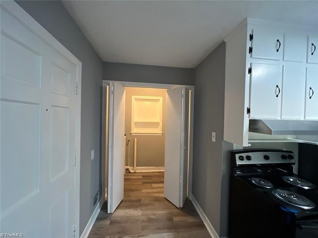 kitchen featuring electric range oven, white cabinetry, and light hardwood / wood-style floors