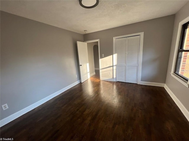 unfurnished bedroom featuring a closet and dark hardwood / wood-style flooring