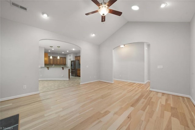 unfurnished living room with visible vents, arched walkways, ceiling fan, and light wood-type flooring