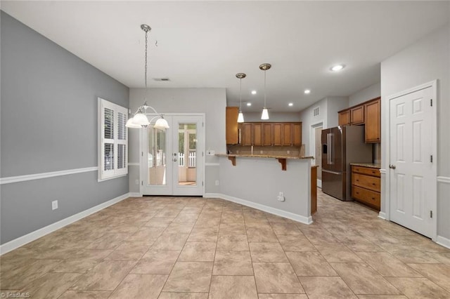 kitchen with decorative light fixtures, brown cabinets, high end refrigerator, a peninsula, and a breakfast bar