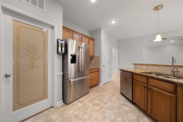 kitchen featuring brown cabinetry, a sink, tasteful backsplash, and stainless steel appliances