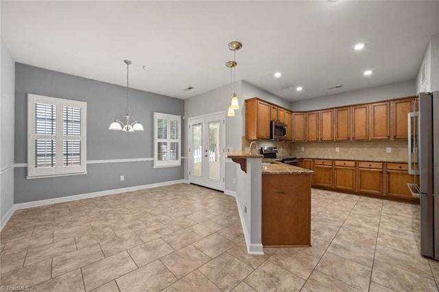 kitchen with brown cabinetry, a peninsula, appliances with stainless steel finishes, and light stone countertops