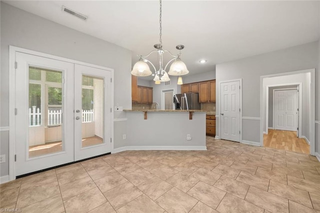 kitchen featuring visible vents, stainless steel refrigerator with ice dispenser, a chandelier, brown cabinets, and french doors