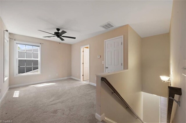 interior space featuring baseboards, visible vents, light colored carpet, and an upstairs landing