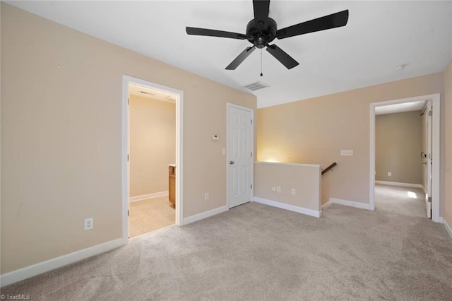spare room with carpet floors, ceiling fan, baseboards, and visible vents