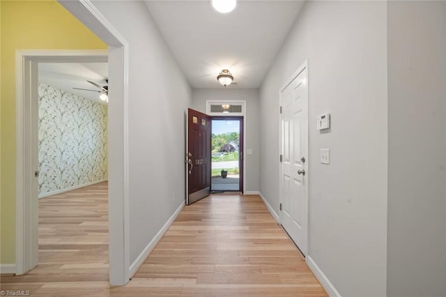 entryway featuring baseboards, ceiling fan, and light wood-style flooring