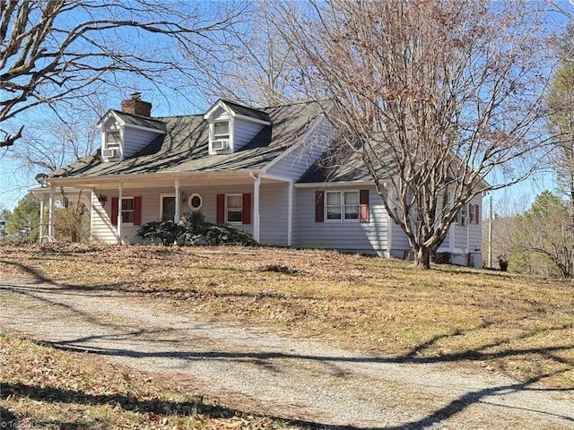 cape cod home with cooling unit, covered porch, driveway, and a chimney