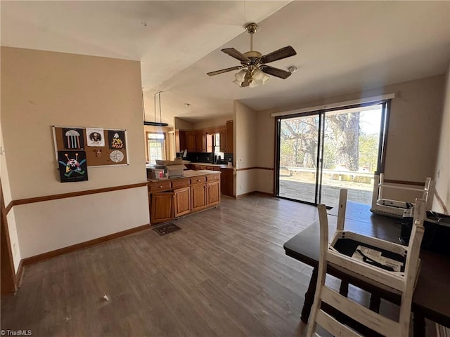 interior space with baseboards, dark wood-type flooring, brown cabinetry, and vaulted ceiling