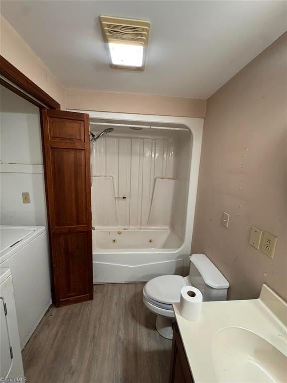 bathroom with toilet, vanity, wood finished floors, washer and dryer, and washtub / shower combination