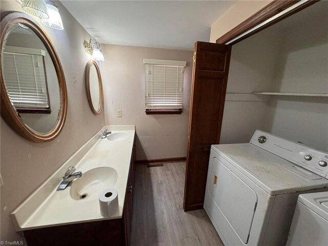 laundry area featuring baseboards, light wood finished floors, laundry area, a sink, and independent washer and dryer