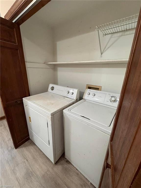 washroom featuring washer and dryer, laundry area, and light wood-style floors