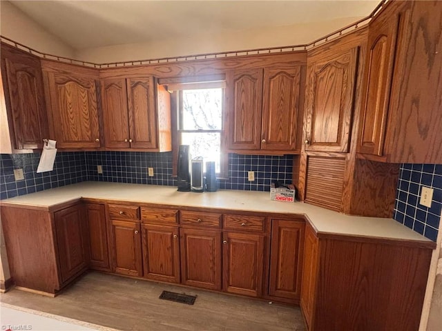 kitchen with brown cabinets, backsplash, and light countertops