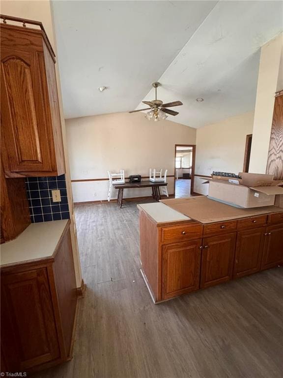 kitchen with a ceiling fan, brown cabinetry, lofted ceiling, dark wood-style flooring, and light countertops