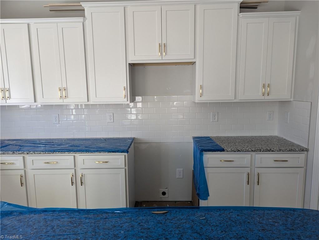 kitchen with white cabinets, stone countertops, and tasteful backsplash