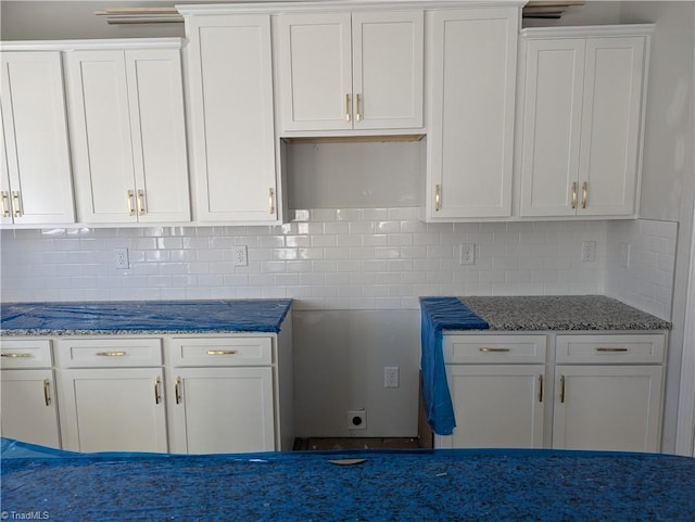 kitchen featuring white cabinets, stone countertops, and backsplash