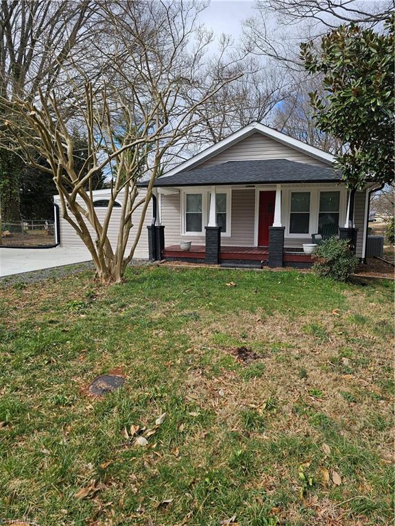 view of front facade featuring a front lawn, concrete driveway, and roof with shingles