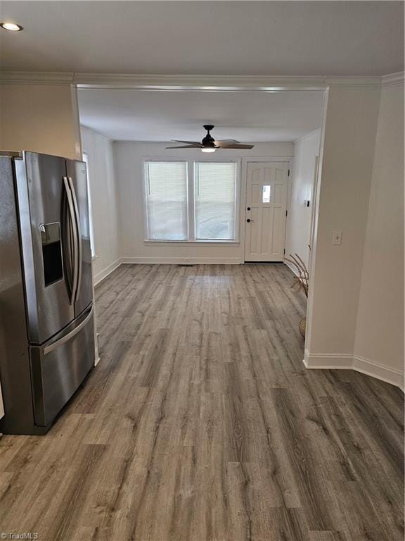 interior space with a ceiling fan, crown molding, baseboards, and wood finished floors