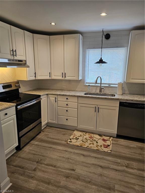 kitchen with under cabinet range hood, a sink, wood finished floors, stainless steel appliances, and white cabinets