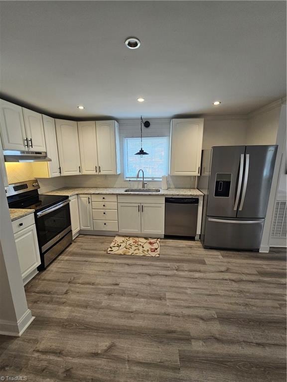 kitchen with dark wood-type flooring, under cabinet range hood, white cabinets, stainless steel appliances, and a sink