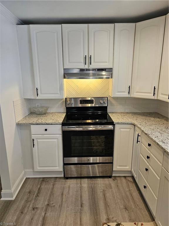 kitchen with light wood-type flooring, under cabinet range hood, stainless steel electric stove, white cabinets, and decorative backsplash