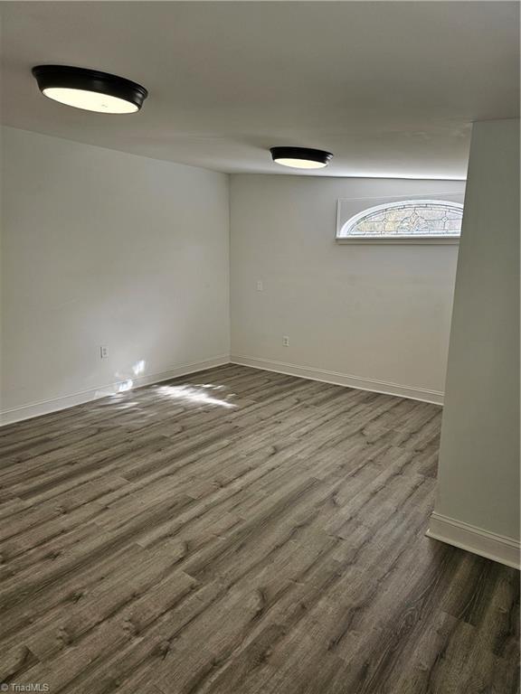 spare room with dark wood finished floors and baseboards