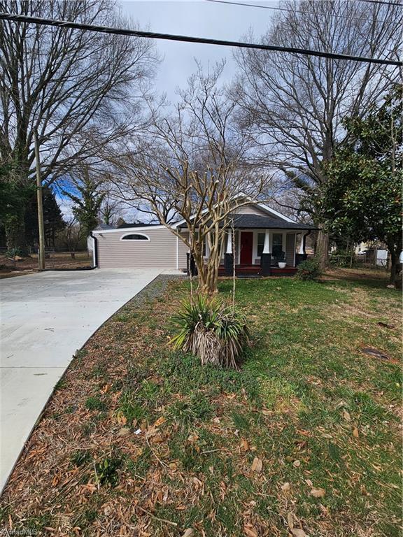 view of front of property featuring a front yard, a porch, and driveway