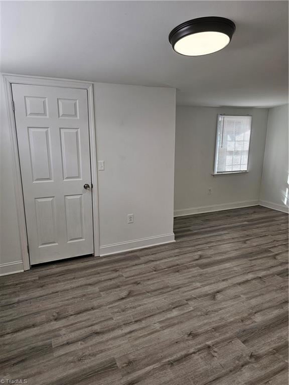 spare room with dark wood-style floors and baseboards