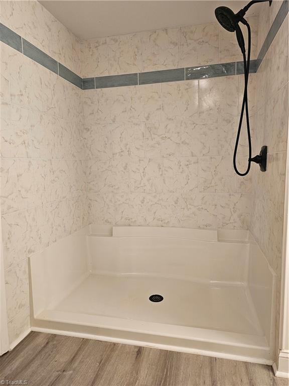 bathroom featuring walk in shower and wood finished floors