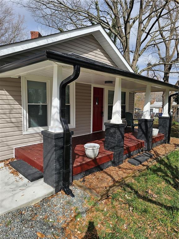 doorway to property with covered porch and a chimney