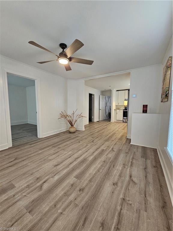 unfurnished living room featuring light wood finished floors, baseboards, and ceiling fan