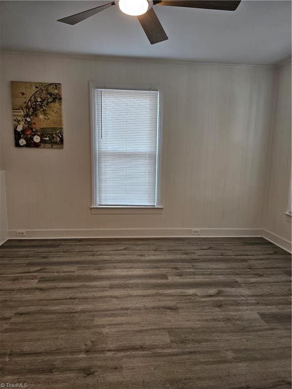 empty room featuring baseboards, dark wood finished floors, a ceiling fan, and ornamental molding