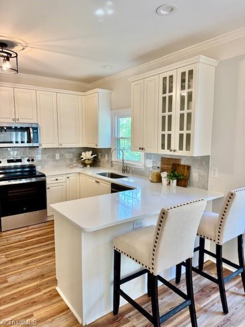 121 Spring Lake Ct, Lexington, NC 27295 - kitchen with stainless steel appliances, crown molding, a peninsula, light countertops, and light wood-type flooring