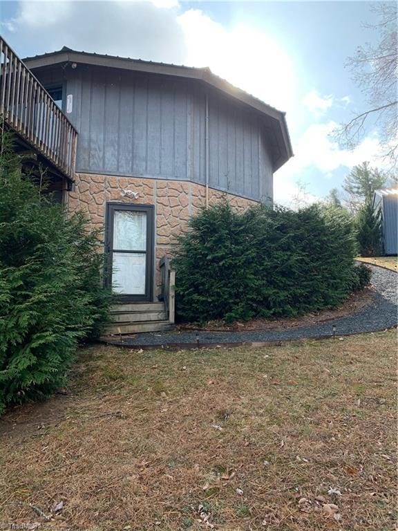 view of property exterior featuring entry steps, stone siding, and a yard