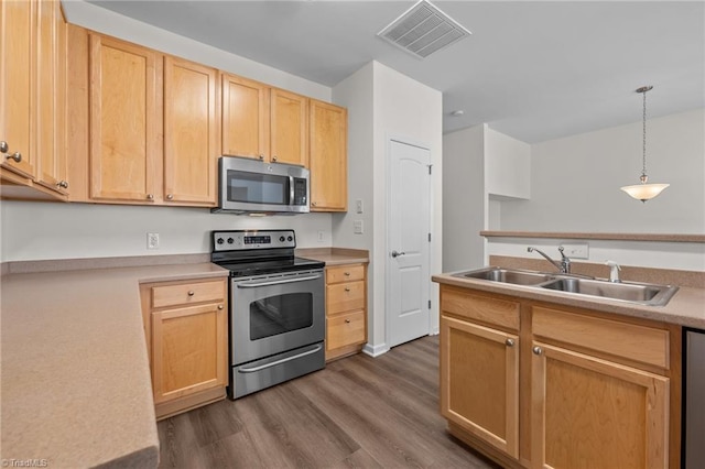 kitchen featuring light brown cabinetry, a sink, dark wood finished floors, stainless steel appliances, and visible vents