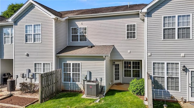 back of house featuring fence, central AC unit, and a lawn