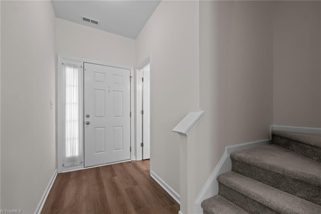 foyer featuring visible vents, stairs, baseboards, and wood finished floors
