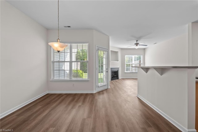 unfurnished living room featuring baseboards, dark wood-style floors, ceiling fan, and a fireplace