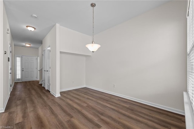 unfurnished dining area with baseboards and dark wood-style floors