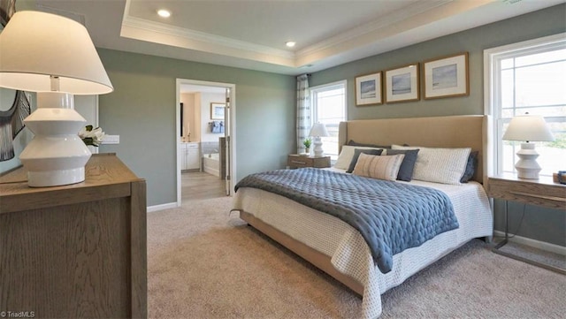 bedroom with ensuite bathroom, a raised ceiling, light colored carpet, and crown molding