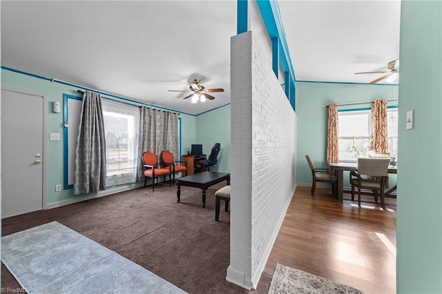 living area featuring ceiling fan, ornamental molding, dark wood-type flooring, and vaulted ceiling