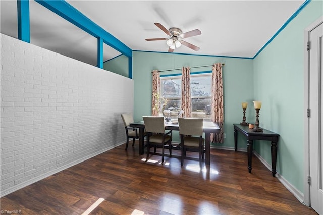 dining room with ceiling fan, dark hardwood / wood-style flooring, brick wall, and vaulted ceiling