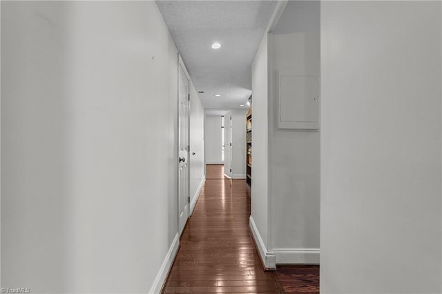 corridor featuring a textured ceiling and dark wood-type flooring