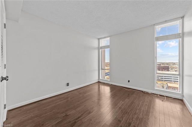 empty room featuring a textured ceiling and dark wood-type flooring