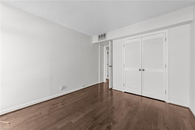 unfurnished bedroom with a textured ceiling, a closet, and dark hardwood / wood-style floors