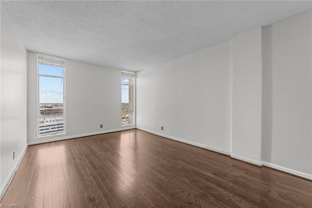 spare room with a textured ceiling and dark hardwood / wood-style floors